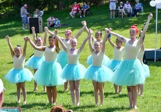 A group of girls in  bright blue tutus dancing 